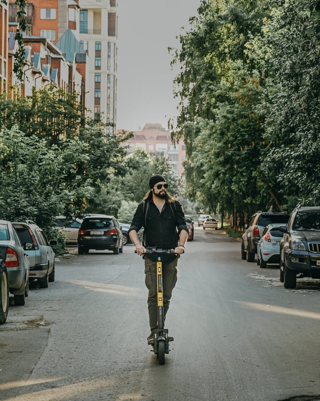 Unrecognizable man riding electric kick scooter on street